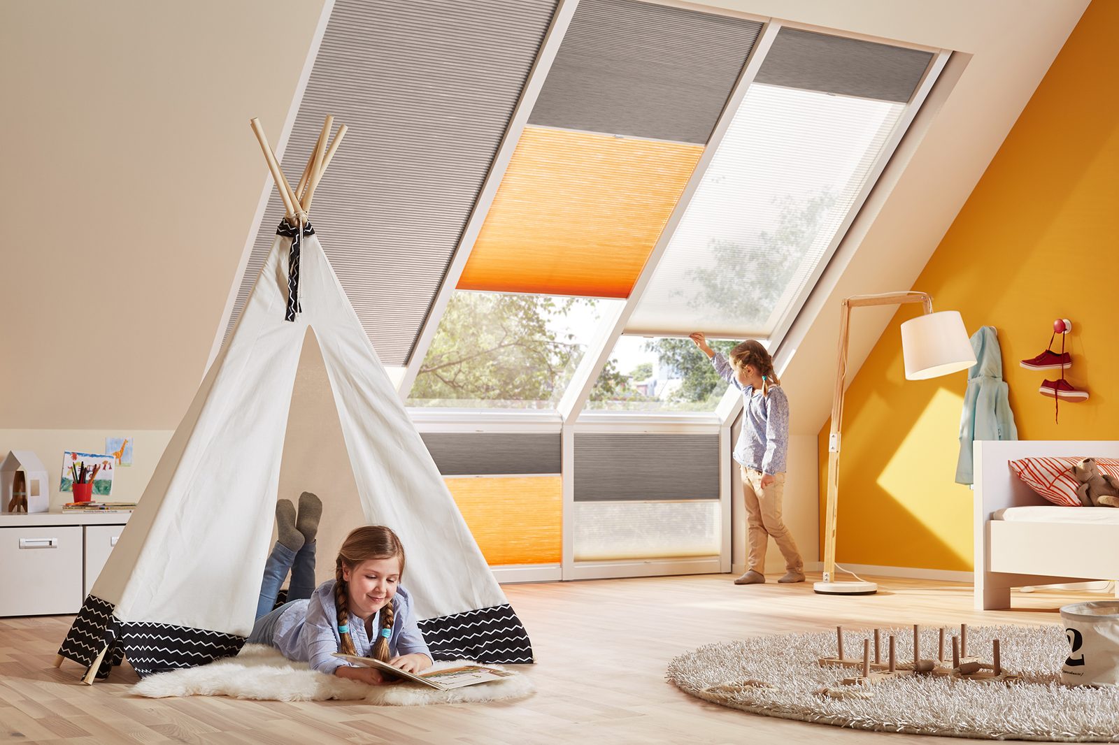 Wabenplissees in Grau und Orange an den Dachfenstern eines Kinderzimmers